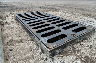 Yolda ya da kaldırımda yeni yağmur suyu ızgarası, beton döşeme. Şiddetli yağmurda suyu boşaltmak için şehir kanalizasyon sistemi