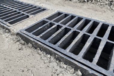 Yolda ya da kaldırımda yeni yağmur suyu ızgarası, beton döşeme. Şiddetli yağmurda suyu boşaltmak için şehir kanalizasyon sistemi