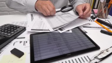 İş analizi ve muhasebe konsepti. Belge, hesap çizelgesi, hesap makinesi ve tablet bilgisayar kullanarak çalışan bir işadamı. Ofis masası kapanıyor.. 