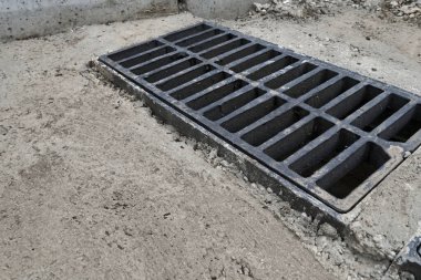 Yolda ya da kaldırımda yeni yağmur suyu ızgarası, beton döşeme. Şiddetli yağmurda suyu boşaltmak için şehir kanalizasyon sistemi