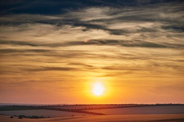 Güzel bir günbatımında buğday tarlası, güneş ışığı ve bulutlar