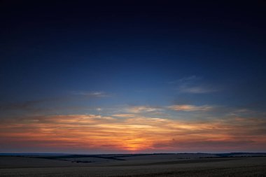 Güzel bir günbatımında buğday tarlası, güneş ışığı ve bulutlar