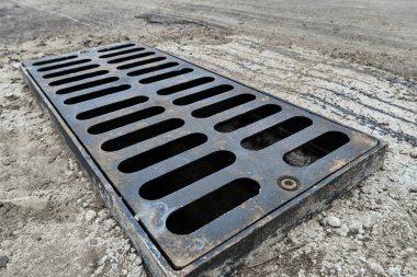 Yolda ya da kaldırımda yeni yağmur suyu ızgarası, beton döşeme. Şiddetli yağmurda suyu boşaltmak için şehir kanalizasyon sistemi