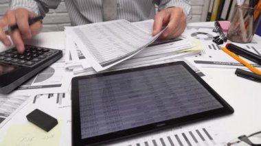 İş analizi ve muhasebe konsepti. Belge, hesap çizelgesi, hesap makinesi ve tablet bilgisayar kullanarak çalışan bir işadamı. Ofis masası kapanıyor.. 