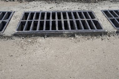 Yolda ya da kaldırımda yeni yağmur suyu ızgarası, beton döşeme. Şiddetli yağmurda suyu boşaltmak için şehir kanalizasyon sistemi