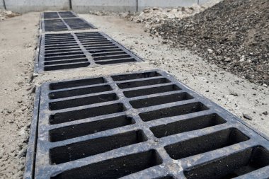 Yolda ya da kaldırımda yeni yağmur suyu ızgarası, beton döşeme. Şiddetli yağmurda suyu boşaltmak için şehir kanalizasyon sistemi