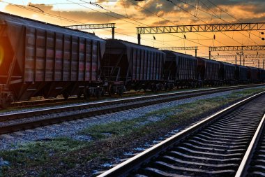 Demiryolu ve vagonlar güzel bir gün batımında, dramatik gökyüzü ve güneş ışığı