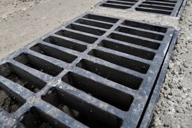 Yolda ya da kaldırımda yeni yağmur suyu ızgarası, beton döşeme. Şiddetli yağmurda suyu boşaltmak için şehir kanalizasyon sistemi
