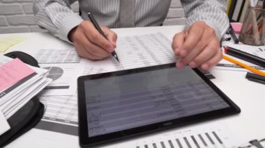 İş analizi ve muhasebe konsepti. Belge, hesap çizelgesi, hesap makinesi ve tablet bilgisayar kullanarak çalışan bir işadamı. Ofis masası kapanıyor.. 