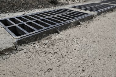 Yolda ya da kaldırımda yeni yağmur suyu ızgarası, beton döşeme. Şiddetli yağmurda suyu boşaltmak için şehir kanalizasyon sistemi