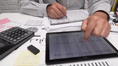İş analizi ve muhasebe konsepti. Belge, hesap çizelgesi, hesap makinesi ve tablet bilgisayar kullanarak çalışan bir işadamı. Ofis masası kapanıyor.. 