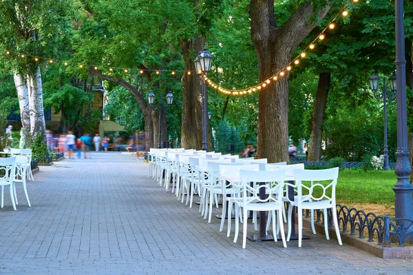 Open Air Street Cafe Outdoor Białe Krzesła Stoły Ozdobione Oświetleniem — Zdjęcie stockowe
