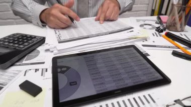 İş analizi ve muhasebe konsepti. Belge, hesap çizelgesi, hesap makinesi ve tablet bilgisayar kullanarak çalışan bir işadamı. Ofis masası kapanıyor..