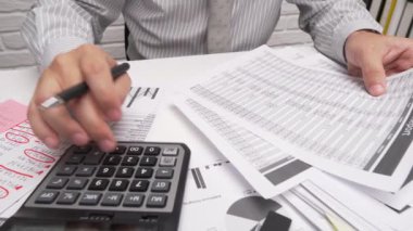 İş analizi ve muhasebe konsepti. Belge, hesap çizelgesi, hesap makinesi ve tablet bilgisayar kullanarak çalışan bir işadamı. Ofis masası kapanıyor.. 