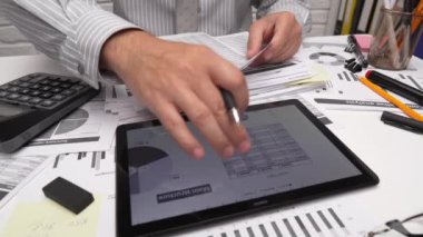İş analizi ve muhasebe konsepti. Belge, hesap çizelgesi, hesap makinesi ve tablet bilgisayar kullanarak çalışan bir işadamı. Ofis masası kapanıyor.. 