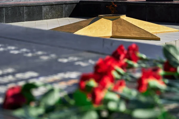 flowers on the memorial to fallen soldiers, eternal flame, red carnations on black marble, Russian text of soldiers military rank - sergeant,major, colonel,Lieutenant Colonel, private, corporal