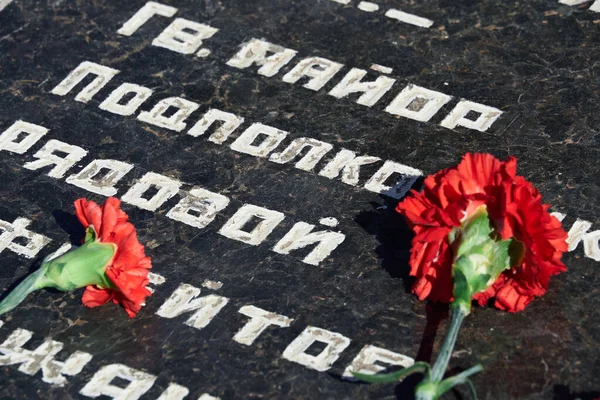 flowers on the memorial to fallen soldiers, red carnations on black marble, Russian text of soldiers military rank - sergeant,major, colonel,Lieutenant Colonel, private, corporal