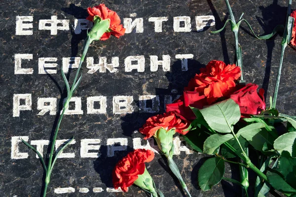 倒れた兵士への追悼の花 黒い大理石の赤いカーネーション 兵士のロシア語の軍事階級のテキスト — ストック写真