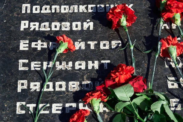 倒れた兵士への追悼の花 黒い大理石の赤いカーネーション 兵士のロシア語の軍事階級のテキスト — ストック写真