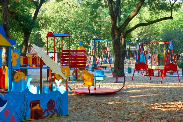 朝早く街の公園で子供の遊び場様々なスイングとカルーセル — ストック写真