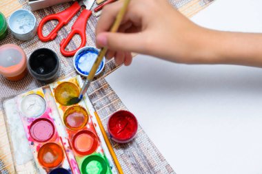 Beyaz bir kağıda suluboya çizen bir kız evde sanatsal bir eser yaratıyor.