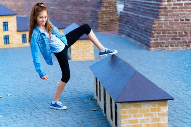 Kız şehir parkında minyatür evlerle oynuyor.