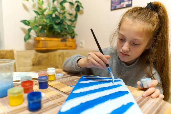 少女は青いグワッシュの段ボールを描き抽象的な背景を作り自宅のキッチンに座り — ストック写真