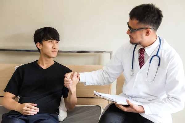 Asian doctor handshake with happy Korean patient man to cheer up after recovering from stomachache sickness on hospital bed. Health care and insurance industry concept.