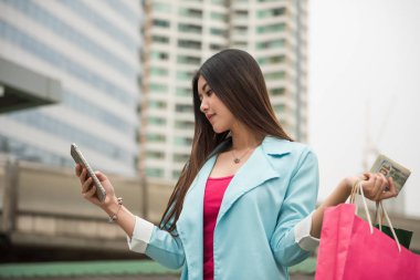 Güzel Asyalı kız ile birçok ABD Doları bill tarama depolamak konumu tarafından 4 g smartphone internetten alışveriş bulmak ve yabancı modern şehir konumda yaz seyahat için. Alışverişkoliğin kavramı.