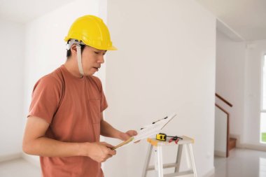 Genç portresi Sarı kask ayrıntılı kağıt planının yeni ev iç tasarımı için okumak ile adam Mühendislik. Furtiture veya kabine modern boş ev için yerleşik olarak bulunur. Gayrimenkul sektöründe