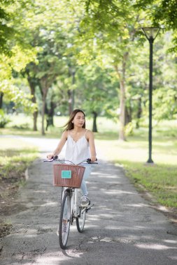 Asyalı güzel mutlu kadın yaz bahçesi Park yeşillik bokeh arka plan ile bir bisiklet sürme sırasında arıyor. Sağlıklı insanlar ve yaşam tarzı konsept spor.