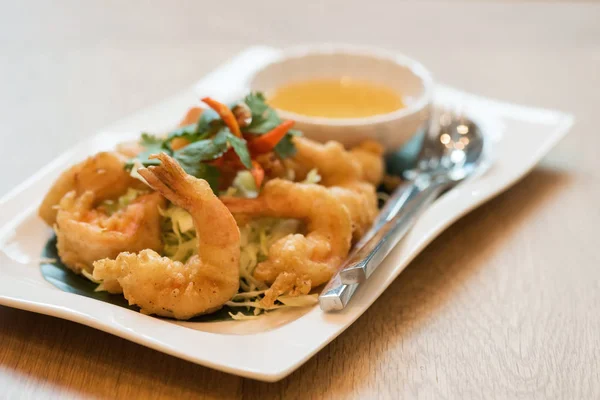 Fried or Tempura Shrimps with sweet and sour  sauce in white plate on wooden table. Thai traditional famous food or cuisine with copy space for text.