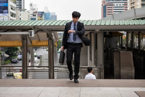 アジア系のビジネスマンを実行し ラッシュ時の街歩きの時間を確認する時計を見ては心配します 鉄道輸送 会議に遅刻の若い男 オフィスの生活やビジネスの競争 — ストック写真