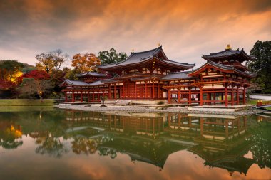 Byodo-in Phoenix hall ışıkla doldu ve sonbahar yaprakları renkleri alacakaranlık gökyüzü, Uji, Kyoto, Japonya ile alacakaranlıkta.