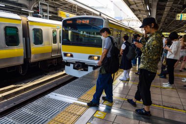 Tokyo, Japonya - 8 Mayıs 2017: Varış trenler ile Jr platform kimliği belirsiz insanlar yerel sarı ve mavi çizgi.