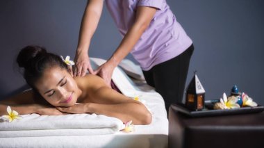 Asyalı güzel tan kadın beyaz Plumeria Spa ile rahatlayın. Vücut bakım tedavisi Tay Petrol Masaj tarafından. Sevimli kız arka sarmal tarafından profesyonel masaj tedavi sahip yatağa eller.