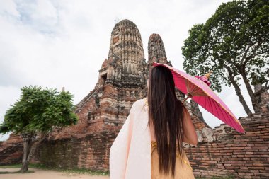 Asya turist kadın Tay geleneksel antika elbise ve şemsiye ziyaret Wat Chai Watthanaram, Ayutthaya, Tayland ile kadeh arka. Antik tapınak mimarisi, turizm.