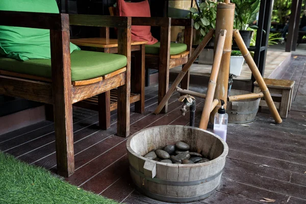 Outdoor chairs to clean foot by water, soap, and natural rocks before Thai massage in spa salon.