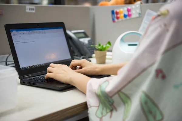 Busy working mother or mom typing on laptop pc computer on table and pumping breastmilk by Automatic breast pump machine with nursing fabric cover. Motherhood in corporate office.