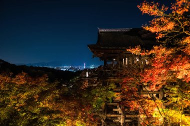 sonbahar yaprakları renkleri büyük ahşap veranda Kiyomizu bina Kiyomizu-dera Tapınağı, Kyoto, Japonya ile yanar. Ünlü Tapınağı landmark Kyoto tower ve kentsel şehir karşı.