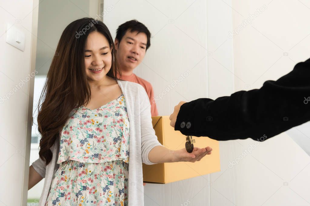 Real estate agent give house key to Asian happy couple owner at front door. Family life to start. buy or purchase home concept with copy space for text. Begin future together.