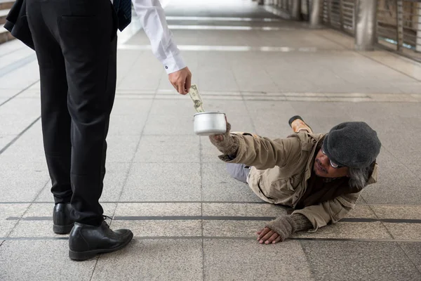 古い米国の ドル紙幣を与えるビジネスの男性には 都市での街歩きに横たわっているホームレスの男性が無効になります 社会問題のコンセプトの貧困 — ストック写真