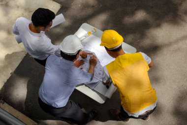 Site Yöneticisi, alan mühendis ve foreman inşaat alanında projet görüşmek üzere kağıt blueprint bakın. Ekip çalışması fo ağır sanayi için kavram. Kopya alanı ile mühendislik takımının üstten görünüm.