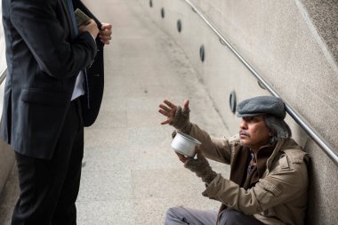 Yaşlı evsiz adam kentsel şehir şehir yürüyüş, bağışlamak tür iş adamı çekme doları bill para elbiseli süre para istemek için elini kaldırsın. Yoksulluk ve sosyal sorun kavramı. Ve sempati ile pay vermek