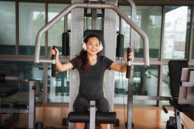 Güzel genç Asyalı kadın egzersiz egzersiz jimnastik salonu makinedeki uygun. Memnun gülümseyen kız onu eğitim süreci ile keyfini çıkarın. Fitness, sağlıklı, spor, yaşam kavramı