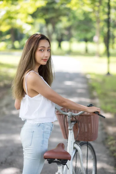 Mulher asiática bonita com bicicleta no parque — Fotografia de Stock