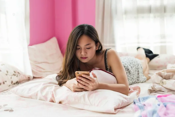 Carino donna giocare smartphone sul letto — Foto Stock