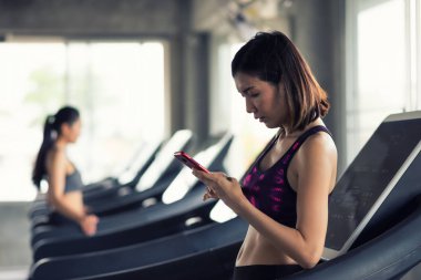 woman play smartphone after workout in gym