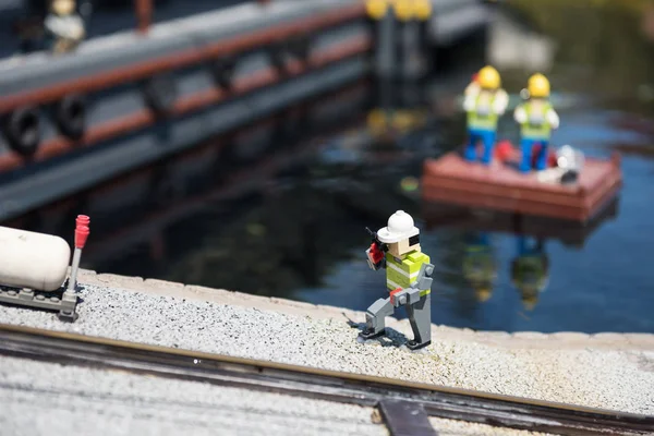Lego model of construction worker phone near canal — Stock Photo, Image