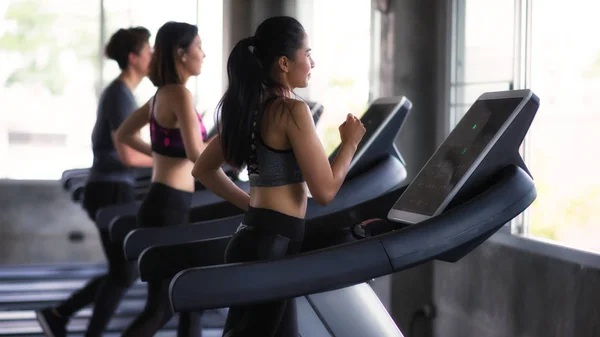 Jóvenes amigos asiáticos corren en cintas de correr en el gimnasio — Foto de Stock